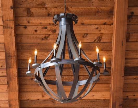 Decorative copper foyer entryway kitchen island pendant light or chandelier with six candles hanging against a wooden wall.