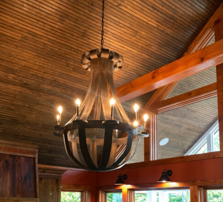copper foyer entryway kitchen island pendant light or chandelier hanging in a room with wooden beams and large windows.