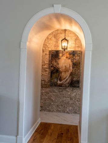 Archway leading to a room with a stone wall and framed picture.