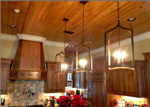 Kitchen with wooden ceiling, pendant lights, and decorative flowers.