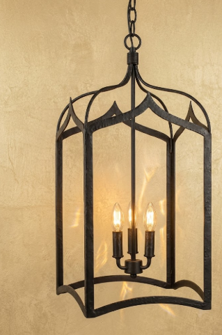 Decorative black metal pendant light with three candle-style lights on a beige background
