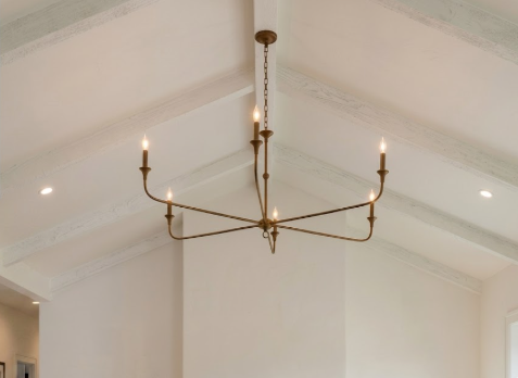 Brass chandelier hanging from a white ceiling