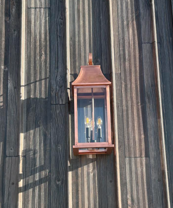 Copper outdoor lantern mounted on a wooden wall