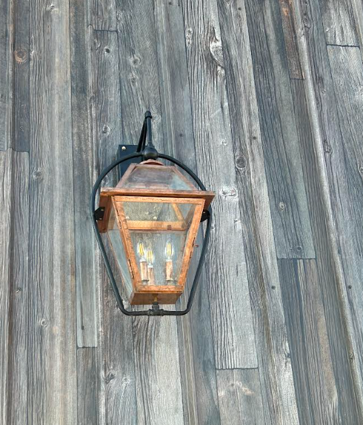 Copper foyer entryway kitchen island  pendant light fixture with three visible bulbs on a dark background