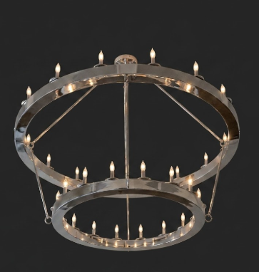 A modern two-ring Foyer entryway chandelier hanging from a ceiling with a brushed silver metal finish and multiple lit candle-style bulbs, shown against a solid black background.