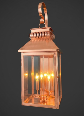 Decorative outdoor lantern with three lights attached to a stone wall.