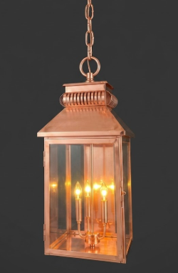 Copper pendant light lantern with glass panels on a dark background