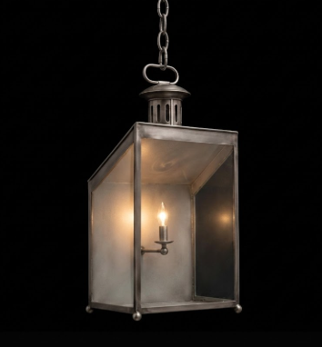 Vintage-style brass hanging pendant light lantern with a light bulb inside on a black background
